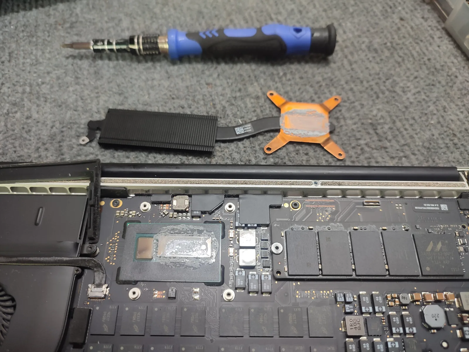 Macbook mở nắp lưng, ổ SSD và bộ tua vít đặt bên cạnh