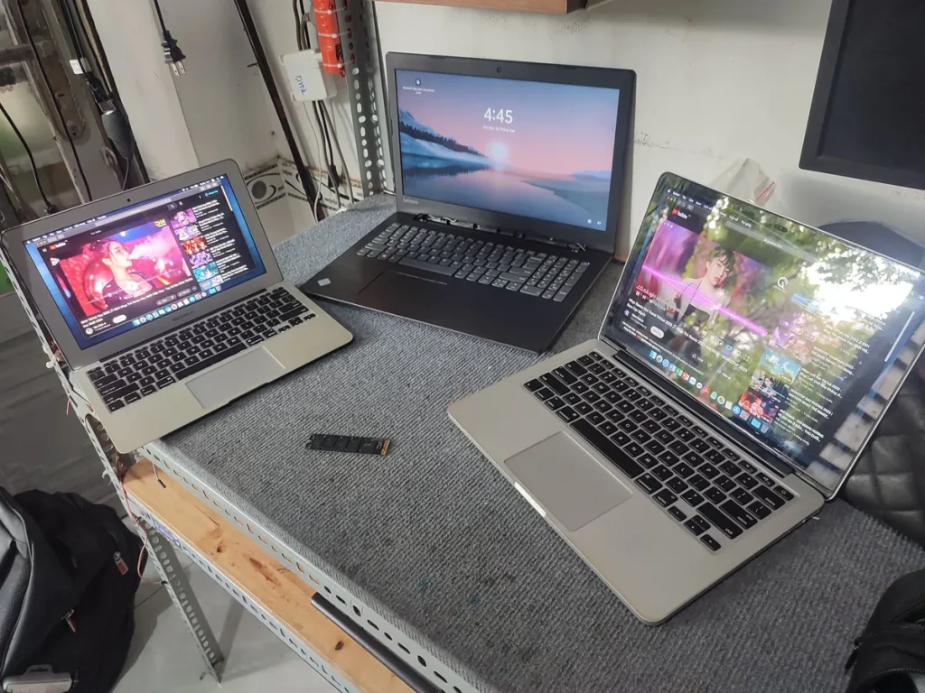 Ba laptop chạy cùng lúc trên bàn, phía trước là một ổ cứng SSD M.2 vừa tháo ra