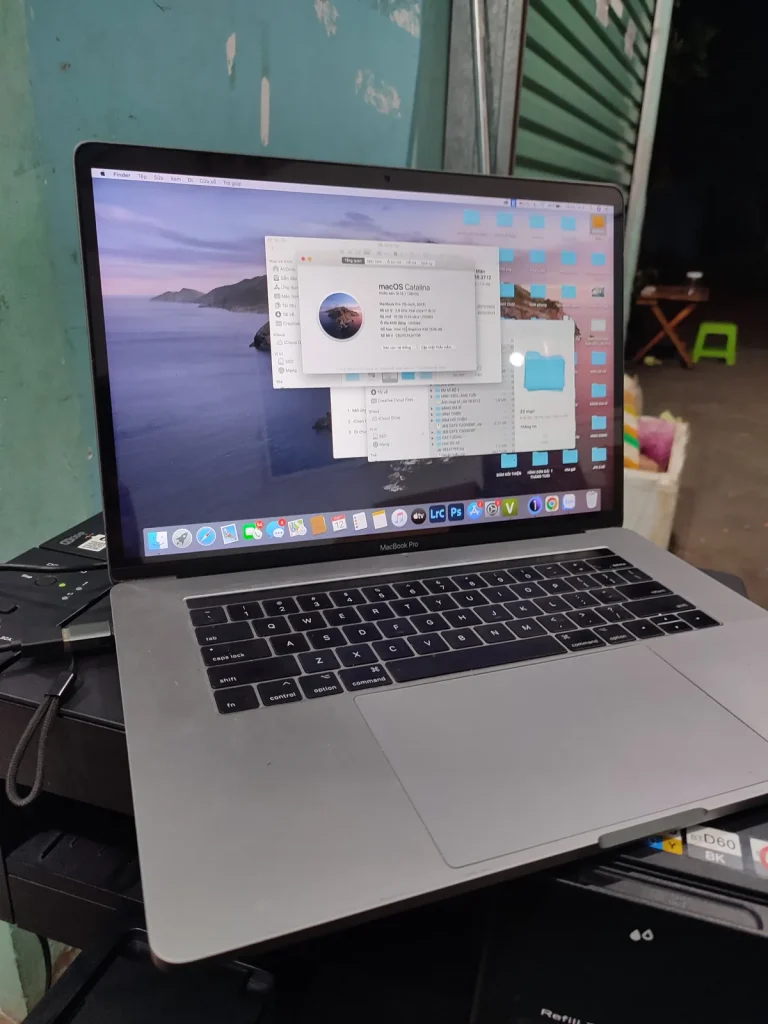 MacBook Pro mở nắp hiển thị bảng thông tin hệ thống macOS Catalina, máy kê trên thiết bị màu đen.